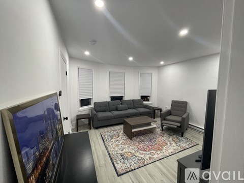 A living room with a grey couch, a coffee table, and a large painting on the wall.