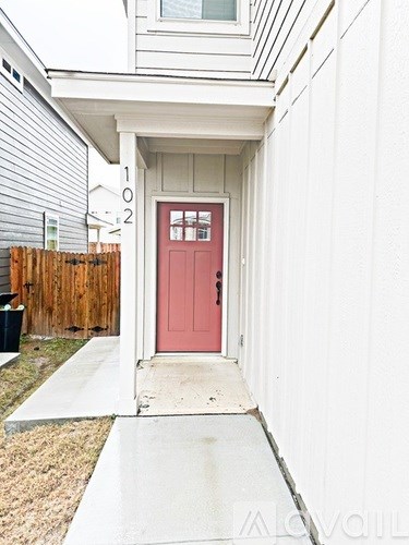 A red door is on the front of a white house.
