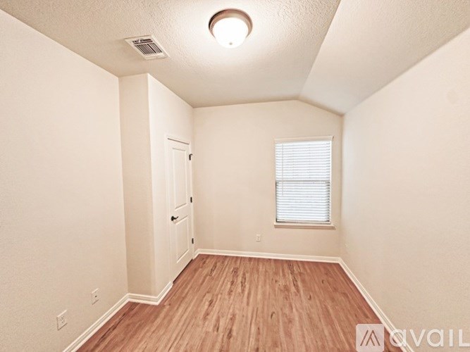 A room with a door, window, and wooden floor.