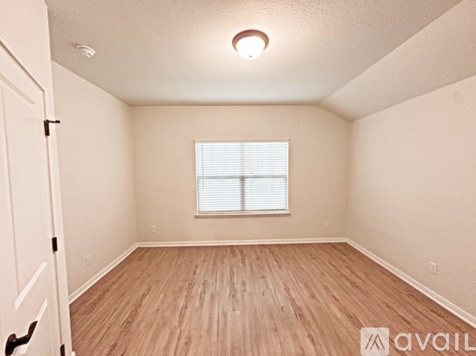 A room with wooden flooring and a window with blinds.