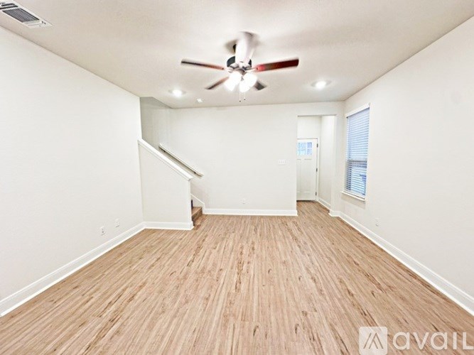 A room with a ceiling fan and wooden flooring.