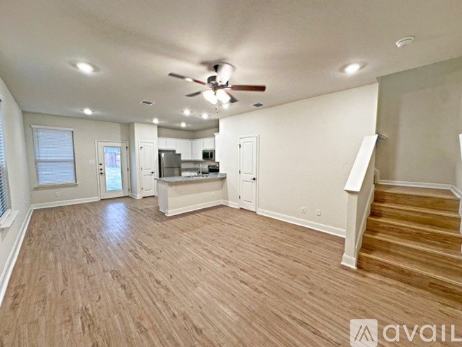 A spacious living room with hardwood floors and a ceiling fan.