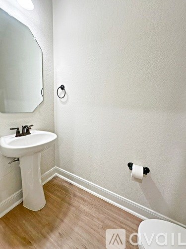 A white pedestal sink with a mirror above it in a small bathroom.