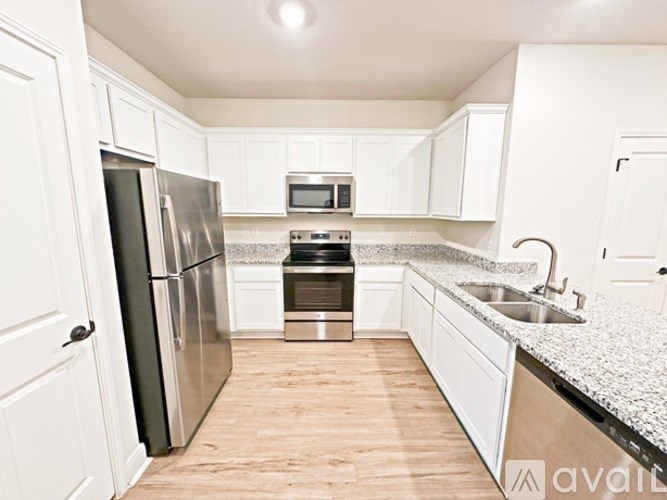 A kitchen with white cabinets and a stainless steel refrigerator.