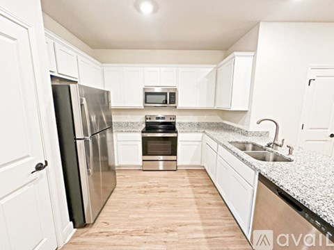 A kitchen with white cabinets and a stainless steel refrigerator.