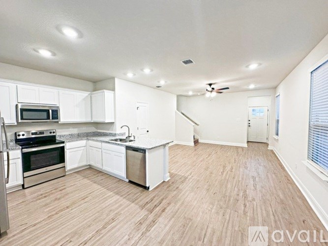 A kitchen with white cabinets and a wooden floor.