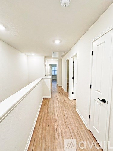 A long hallway with white walls and wood floors.