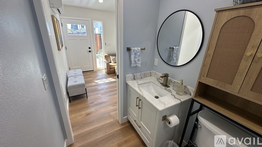A bathroom with a sink, mirror, and wooden floors.