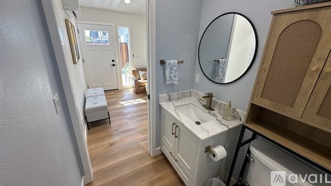A bathroom with a sink, mirror, and wooden floors.