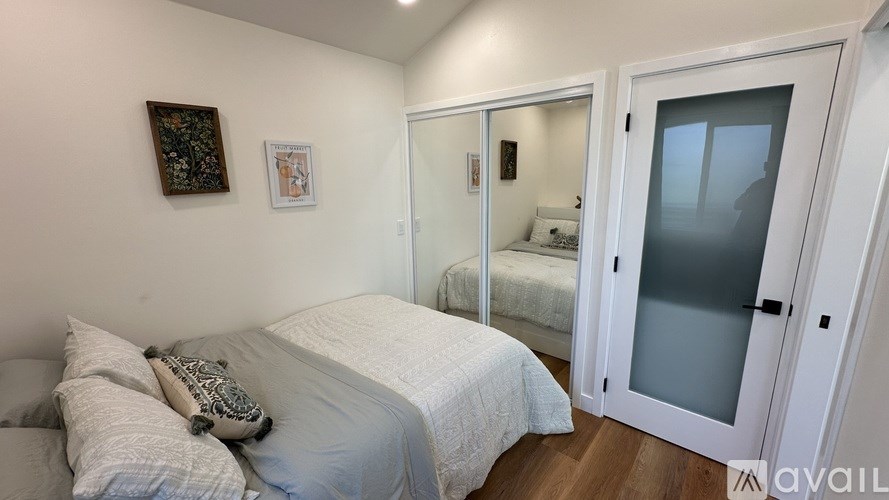 A bedroom with a bed, a mirror, and a framed picture on the wall.