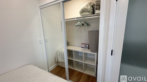 A bedroom with a white bed and a white closet with a mirror.