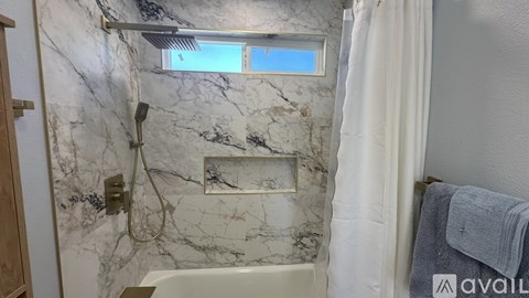 A bathroom with marble walls and a white shower curtain.