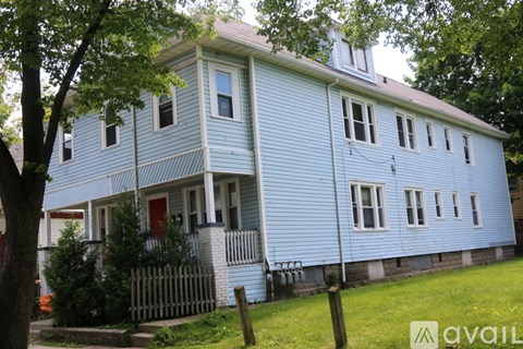 A blue house with a red door and a white picket fence.