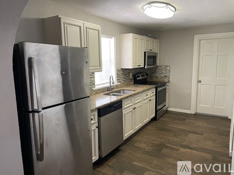 A kitchen with a stainless steel refrigerator and wooden flooring.