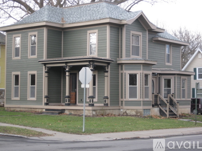 A two-story house with a greenish exterior and a white sign in front.