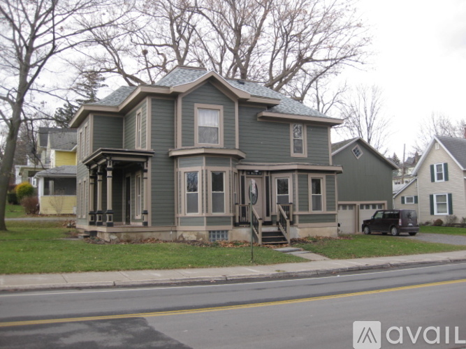 A two-story house with a front porch and a car parked in front.