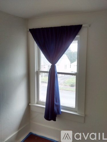 A window with a blue curtain in the corner of a room.
