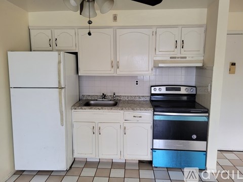 A kitchen with white cabinets and a white fridge.