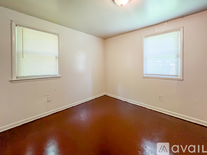 A room with brown floors and two windows.