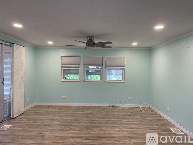 A room with a ceiling fan and two windows.