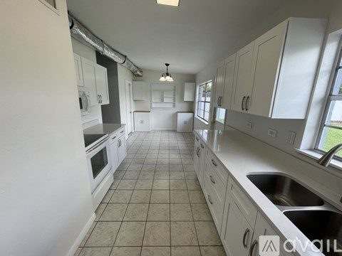 A kitchen with white cabinets and a tiled floor.