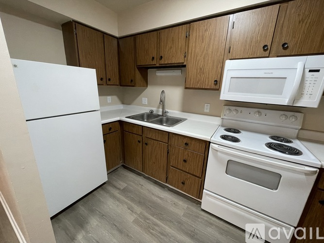 A kitchen with white appliances and wooden cabinets.