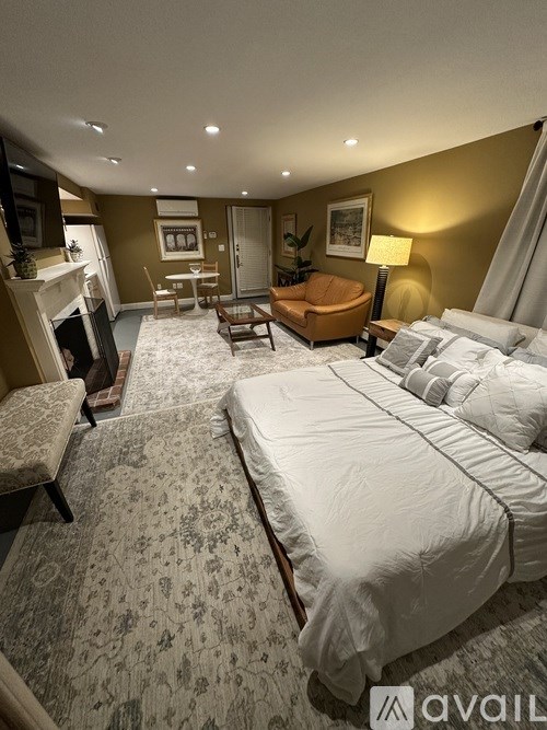 A large bed with a white comforter is in the center of a well-furnished bedroom.