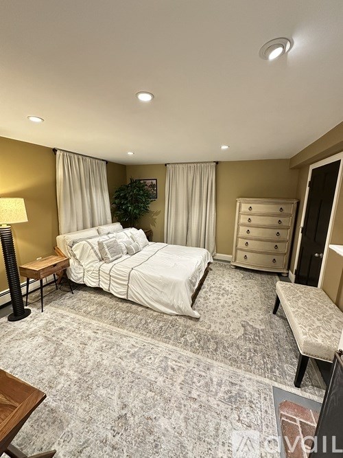 A bedroom with a large bed, a dresser, and a bench.