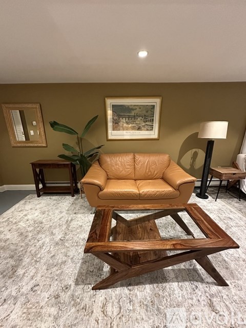A tan leather sofa sits in a living room with a wooden coffee table in front of it.