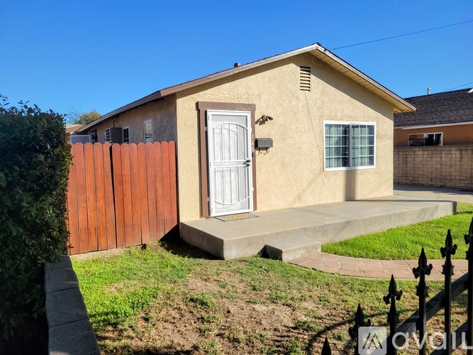 A small house with a white door and a brown fence.