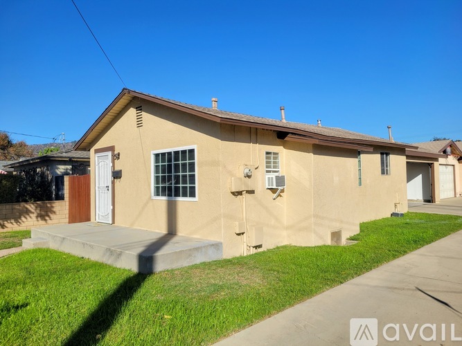 A beige house with a white door and a window is for sale.