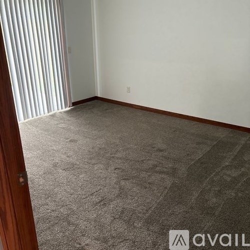 A room with a carpeted floor and a door on the left.