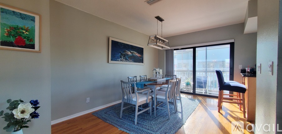 A dining room with a table and chairs and a painting on the wall.