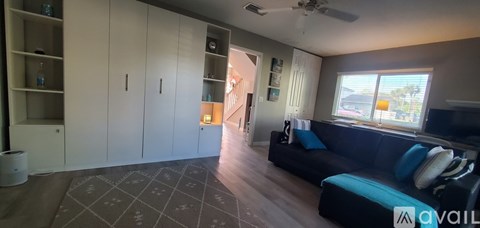 A living room with a black couch and a fan.