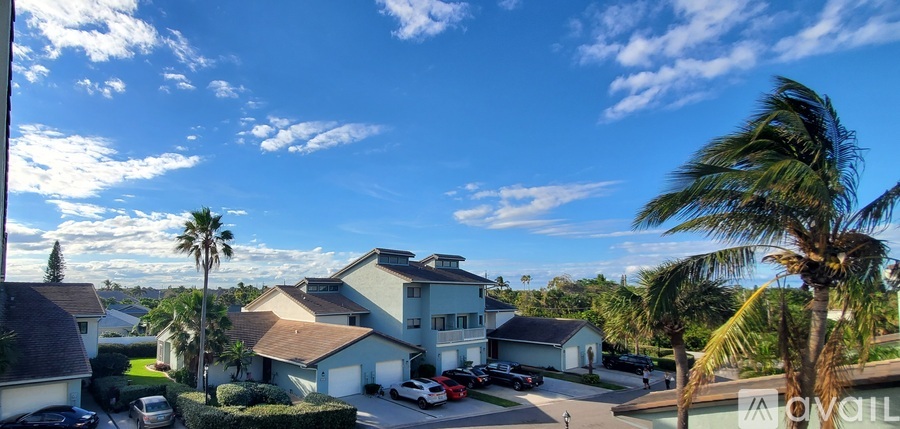 A house with a car parked in front and palm trees around.