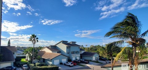 A house with a car parked in front and palm trees around.