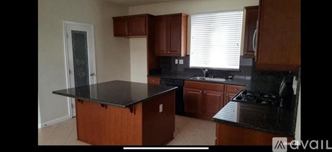 A kitchen with wooden cabinets and black countertops.