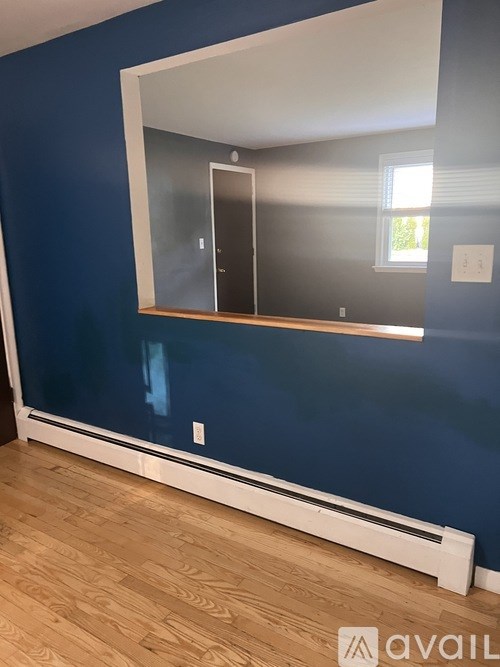 A large mirror hangs on a blue wall above a wooden floor.