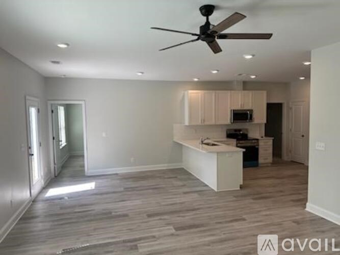 A spacious room with a ceiling fan and a kitchen area.