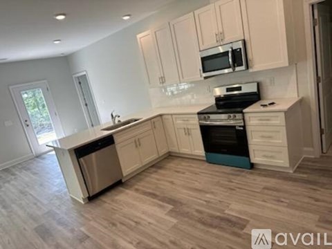 A kitchen with white cabinets and a wooden floor.