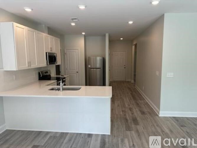 A kitchen with white cabinets and a white island with a sink.