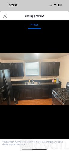 A kitchen with black cabinets and a wooden floor.