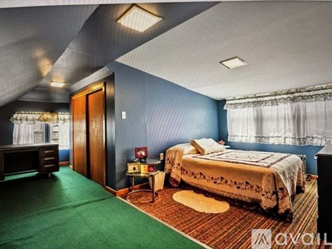 A bedroom with a bed, nightstand, and a desk.