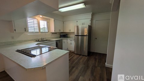 A kitchen with a stainless steel refrigerator and a countertop with a window.