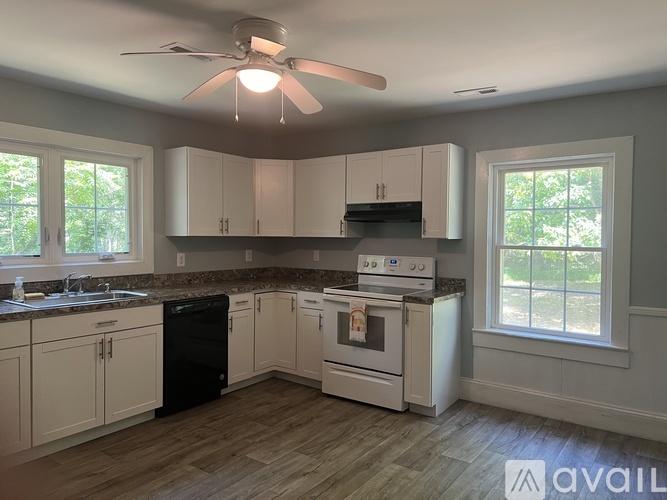 A kitchen with white cabinets and a black dishwasher.