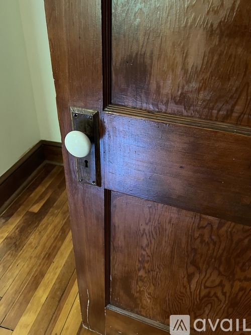 A white knob is on a wooden door.