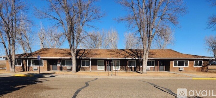 A building with a brown roof and a parking lot in front.