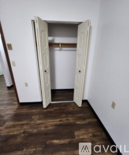 A room with a white door and a brown floor.