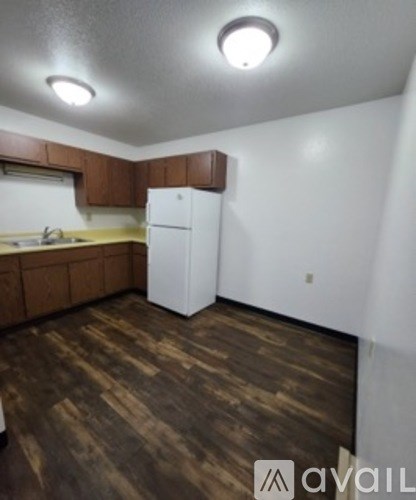 A kitchen with brown cabinets and a white fridge.