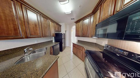 A kitchen with brown cabinets and a black microwave.